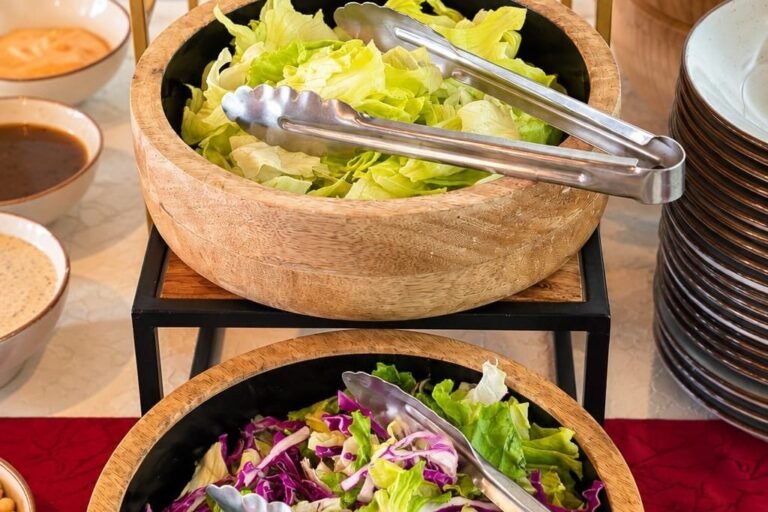 Fresh salad bowls with serving tongs at a Grandeur Hospitality live counter