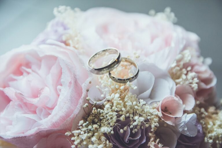 Wedding rings resting on a pink peony bouquet