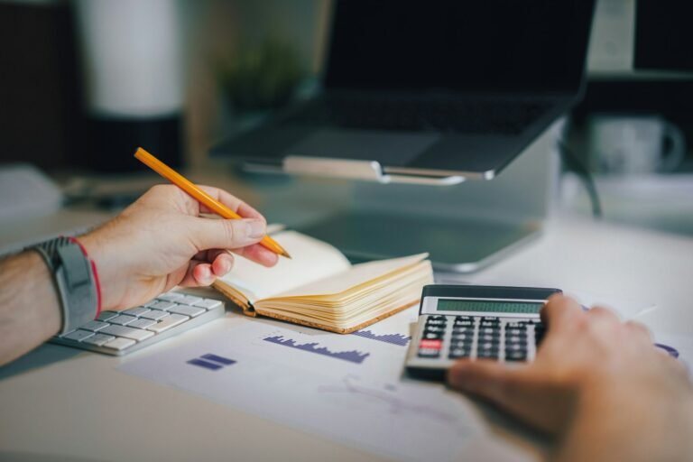 Hands using a calculator while planning a budget at a desk